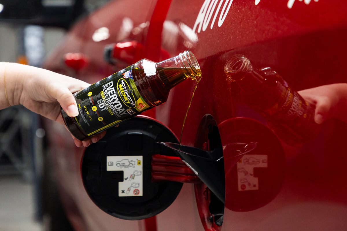 Pouring Everyday Diesel Treatment into the fuel filler of a red vehicle